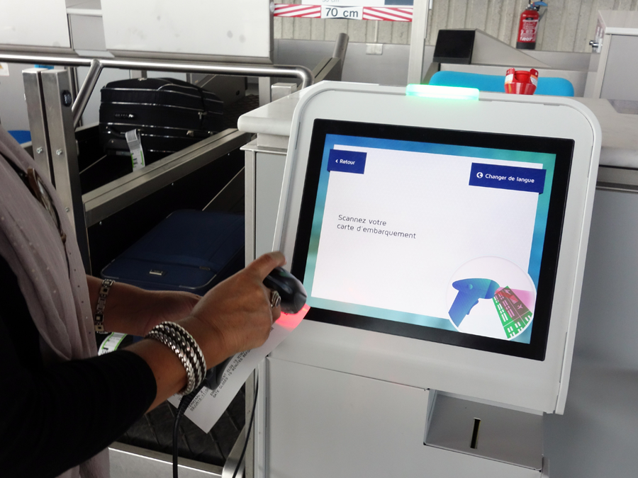 Une utilisatrice se sert de la borne tactile pour enregistrer ses bagages.