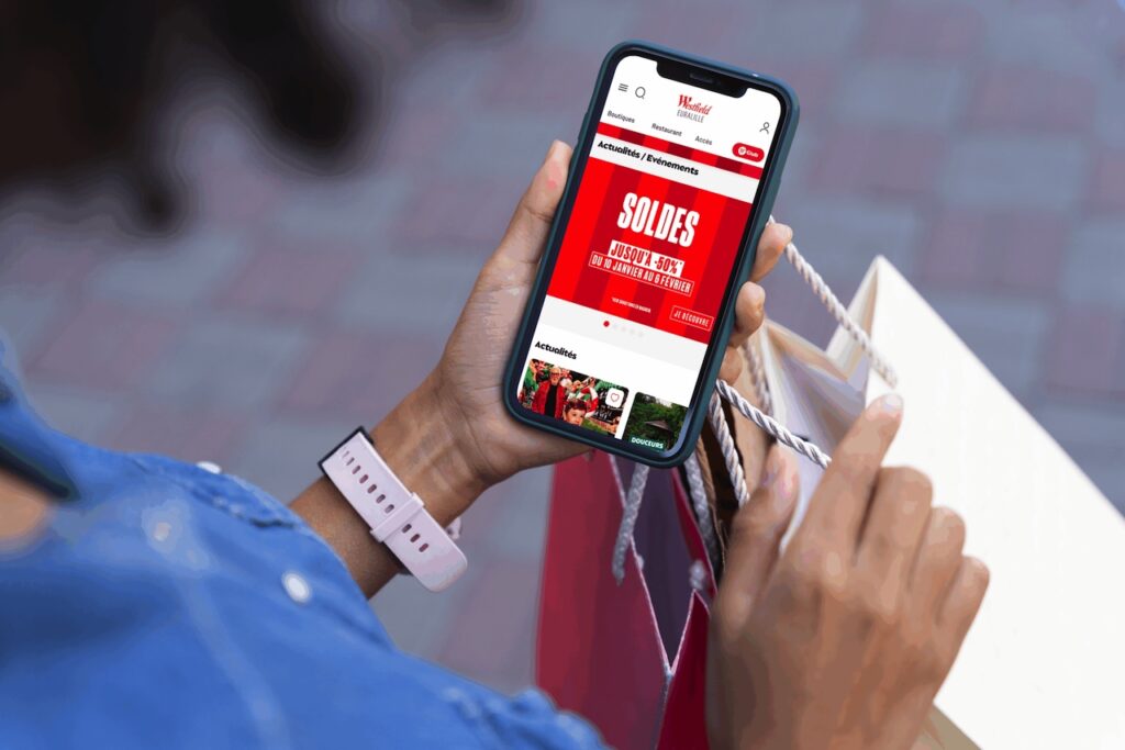Une personne consulte l'application Westfield sur son mobile dans un centre commercial.